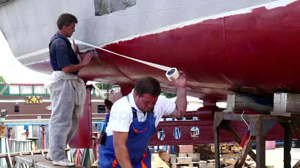 Trabajador pegue una cinta adhesiva en metal de viejo barco oxidado en el astillero en el puerto . — Vídeo de stock