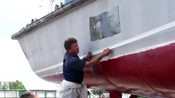 Pracownik trzymać taśmy klejącej na metalu stary zardzewiały statek w stoczni w porcie. — Wideo stockowe
