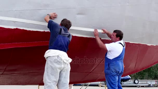 Worker stick an adhesive tape on metal of old rusty ship at shipyard in port. — Stock Video