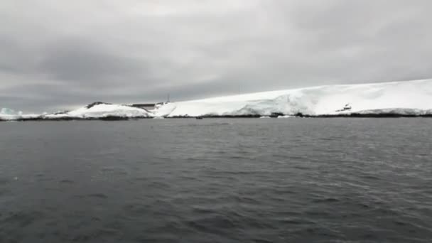 Casa abandonada Superficie del agua y costa de nieve del desierto en el océano de la Antártida . — Vídeos de Stock