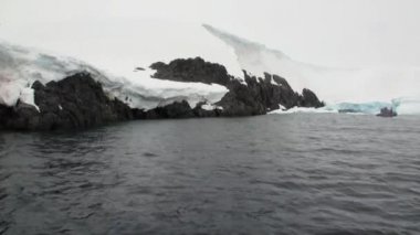 Antarktika'nın karlı dağlarda kar üzerinde kana kauçuk tekne insanlarda bakın.