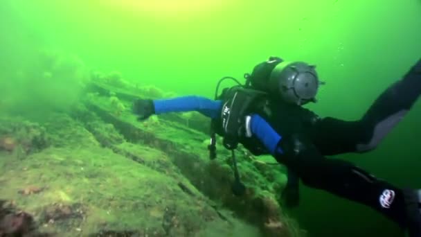 Scuba diver near rusty wreckage shipwreck on beach of White Sea Russia. — Stock Video