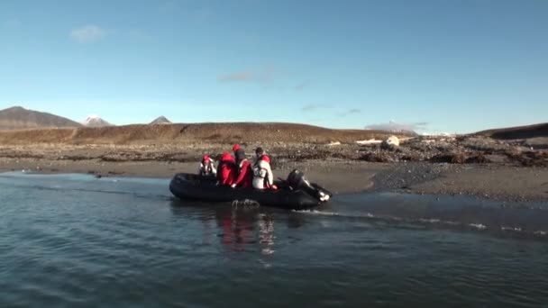 Люди на лодке плывут на фоне гор и пустынь в Северном Ледовитом океане  . — стоковое видео
