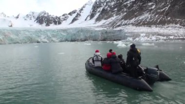 Kuzey Buz Denizi Svalbard dağlarda kar arka plan üzerinde insanlar tekne yelken.