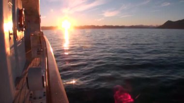 Günbatımı su yüzeyi ve yat Arktik Okyanusu güverte yansıması.