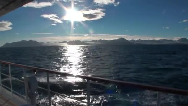 Réflexion soleil à la surface de l'eau sur fond de montagnes enneigées et yacht de pont . — Video