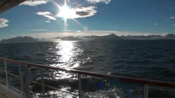 雪に覆われた山々 とデッキ ヨットの背景に水面に反射太陽. — ストック動画
