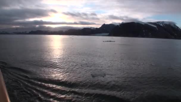 Zasněžené hory a odraz západu slunce ve vodní hladině pohled z paluby jachty. — Stock video