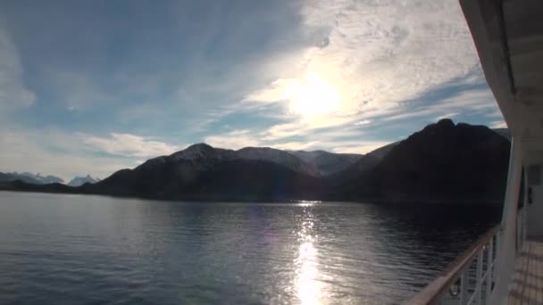 Riflesso sole in superficie d'acqua sullo sfondo di montagne innevate e yacht ponte . — Video Stock