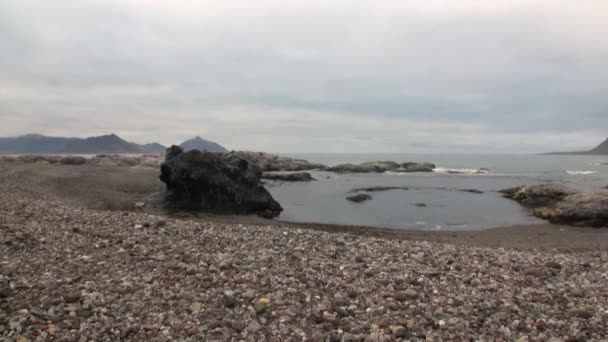 Wüstenküste und Wellen des arktischen Ozeans vor dem Hintergrund der Berge in Spitzbergen. — Stockvideo