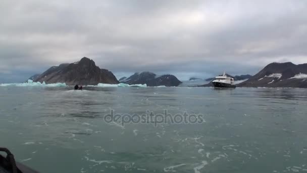 Personer i båten segla och stor yacht på bakgrund av snötäckta berg i Arktis. — Stockvideo