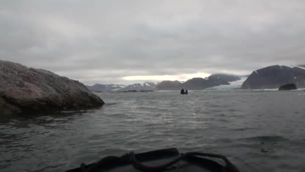 La gente en barco navega en el fondo de las montañas nevadas en el Océano Ártico Svalbard . — Vídeo de stock