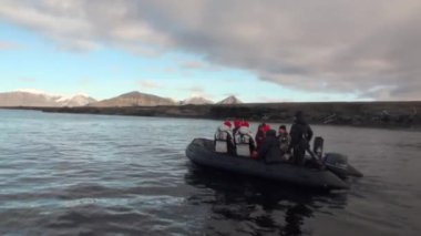 Kuzey Buz Denizi Svalbard dağlarda kar arka plan üzerinde insanlar tekne yelken.