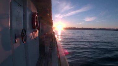 Günbatımı su yüzeyi ve yat Arktik Okyanusu güverte yansıması.