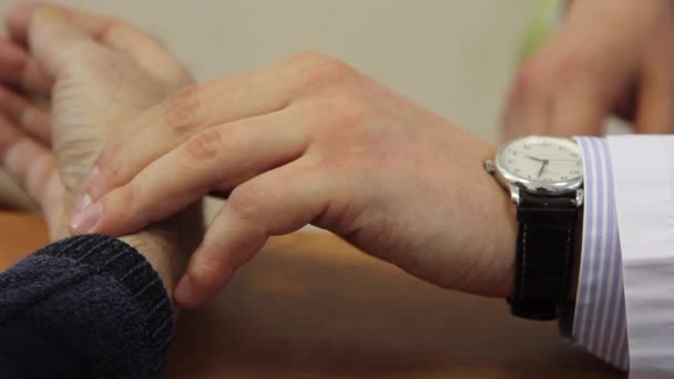 La mano del médico el hombre con el reloj comprueba el pulso del paciente en la clínica . — Vídeo de stock