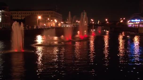 Fontaines lumineuses dans la rivière et des lanternes sur fond de pont à Moscou la nuit. — Video