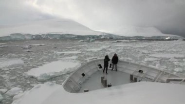 Araştırma seferi Gemideki insanların buz buzdağı Antarktika okyanusun içinde yüzen.