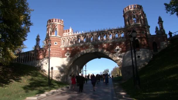 La gente camina cerca del puente de ladrillo rojo en el parque Tsaritsinsky en verano. — Vídeos de Stock