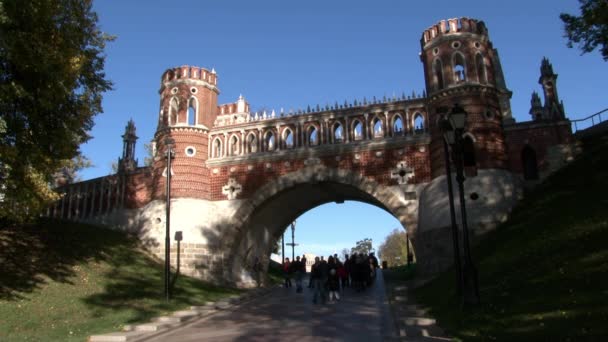 La gente camina cerca del puente de ladrillo rojo en el parque Tsaritsinsky en verano. — Vídeos de Stock