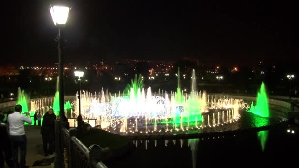 Lidé chodí v noci v blízkosti dancing fountains. — Stock video