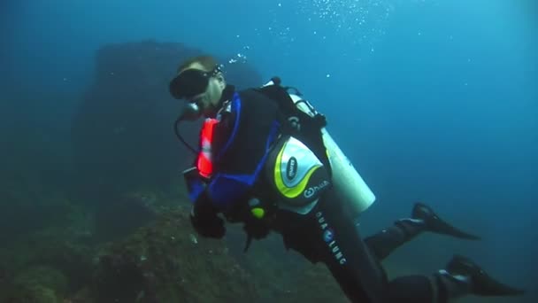 Duikers onderwater op de achtergrond van de zeebodem. — Stockvideo