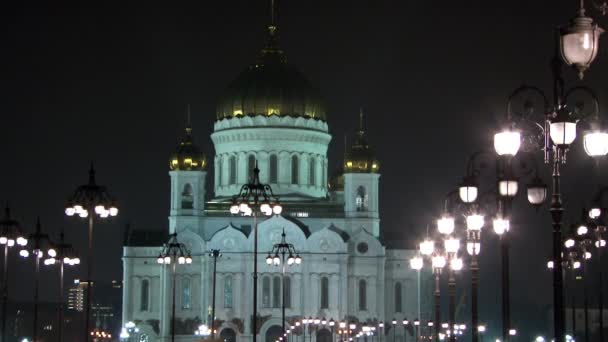 La gente cammina lungo il ponte patriarcale fino alla Cattedrale di Cristo Salvatore di notte . — Video Stock