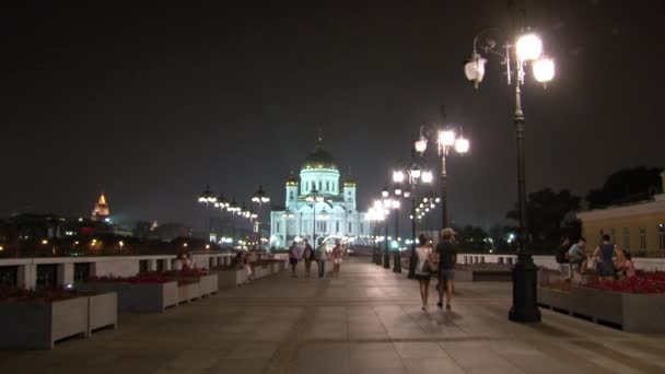 La gente cammina lungo il ponte patriarcale fino alla Cattedrale di Cristo Salvatore di notte . — Video Stock