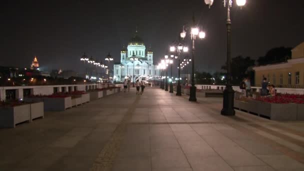 People walk along Patriarchal bridge to Cathedral of Christ Savior at night. — Stock Video