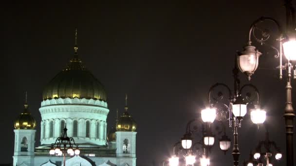 Mensen lopen langs patriarchaal brug naar de kathedraal van Christus Verlosser in de nacht. — Stockvideo