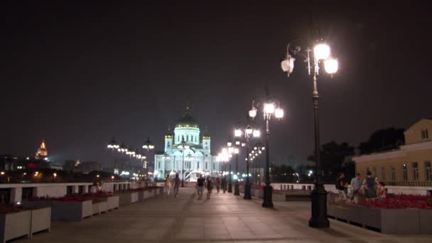 La gente cammina lungo il ponte patriarcale fino alla Cattedrale di Cristo Salvatore di notte . — Video Stock