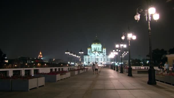 La gente cammina lungo il ponte patriarcale fino alla Cattedrale di Cristo Salvatore di notte . — Video Stock