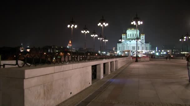 Mensen lopen langs patriarchaal brug naar de kathedraal van Christus Verlosser in de nacht. — Stockvideo