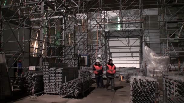 近くの建設現場で建築の金属製の足場で作業する人々. — ストック動画