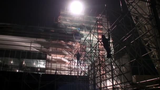 Werknemers aan de bouwers metalen steigers op bouwplaats. — Stockvideo