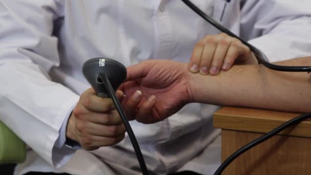 Ruka muže lékaře s tonometr kontroluje puls pacienta v klinice. — Stock video