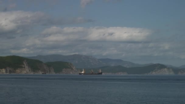 Mořské vlny vodní plochy na pláži pobřeží zelené kamenité skály v Japonsku moři. — Stock video