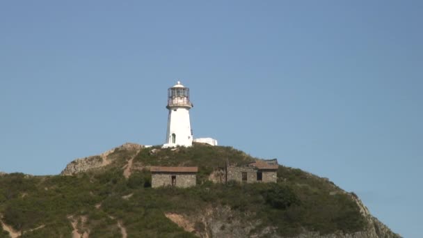 Vuurtoren seamark op groene stenen stenen kustlijn strand in Japan zee. — Stockvideo