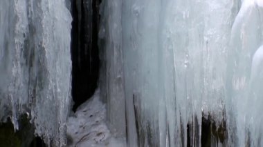 Baykal Gölü 'ndeki doğal buzulun kayaları üzerindeki büyük buz sarkıtları..