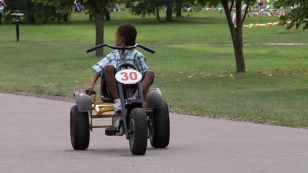 Enfant afro-américain petite fille avec dreadlocks assis sur le vélo sur la route dans le parc . — Video