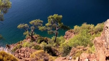 Güneş ışınları kıyı şeridi yakınlarındaki deniz suyunun yüzeyinde oynar ve yatlar körfezde yelken açar..