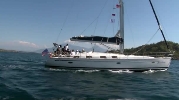La gente navega en yate blanco en el fondo de la costa de montaña en Turquía. — Vídeo de stock