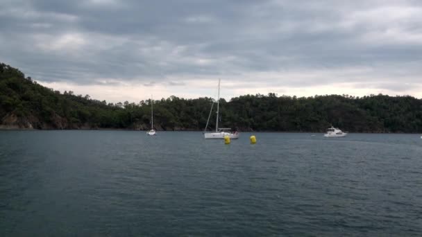 Vit yacht med människor flyter nära bojar i viken. — Stockvideo