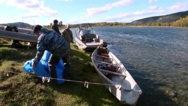 Tourists rest after trip on airboat on banks of Lena River. — Stock Video