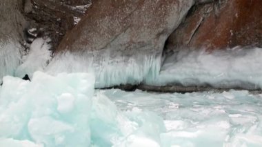 İnsanlar buz içinde donmuş kayaların ve Baykal 'daki doğal buzulların karlarının yanında yürür..
