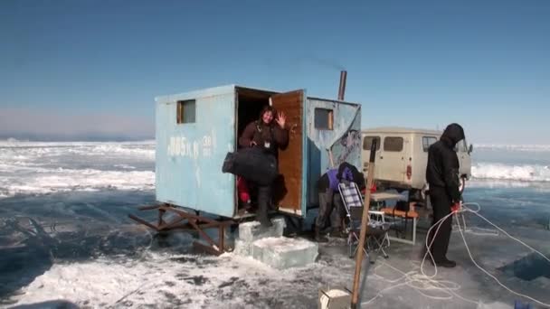 Ludzie podgrzewają saunę przy dużych blokach lodu i otworach lodowych na Baikal.. — Wideo stockowe
