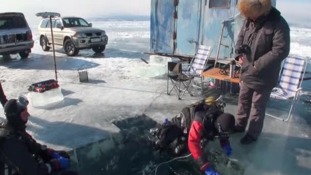 Dykare är nedsänkta under vatten i ishålet i sjön Baikal. — Stockvideo