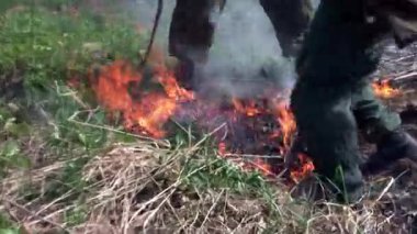 Askeri üniformalı adamlar ormandaki yangını söndürüyor..