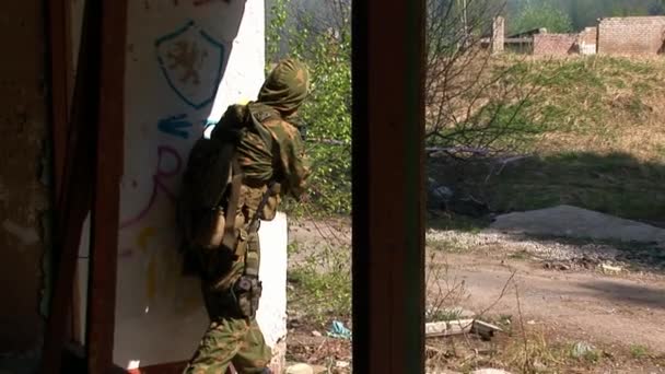 Homme en uniforme militaire avec des armes sur fond de maison détruite . — Video