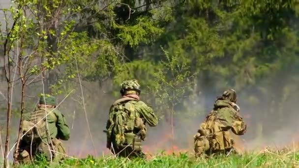 Personas en uniforme en el fondo de fuego militar en el bosque . — Vídeo de stock