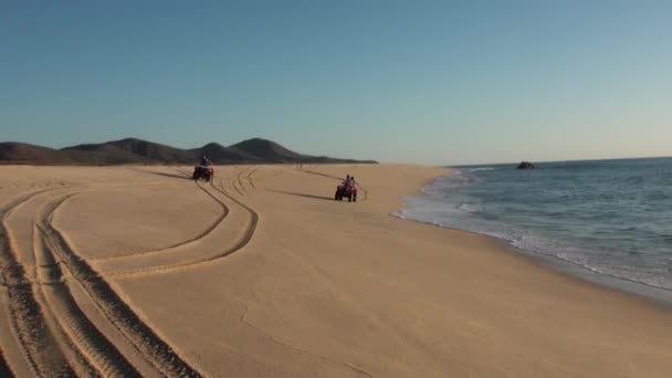 Хлопчик і дівчинка на квадроциклі ATV їздити на піску і махати вітання . — стокове відео